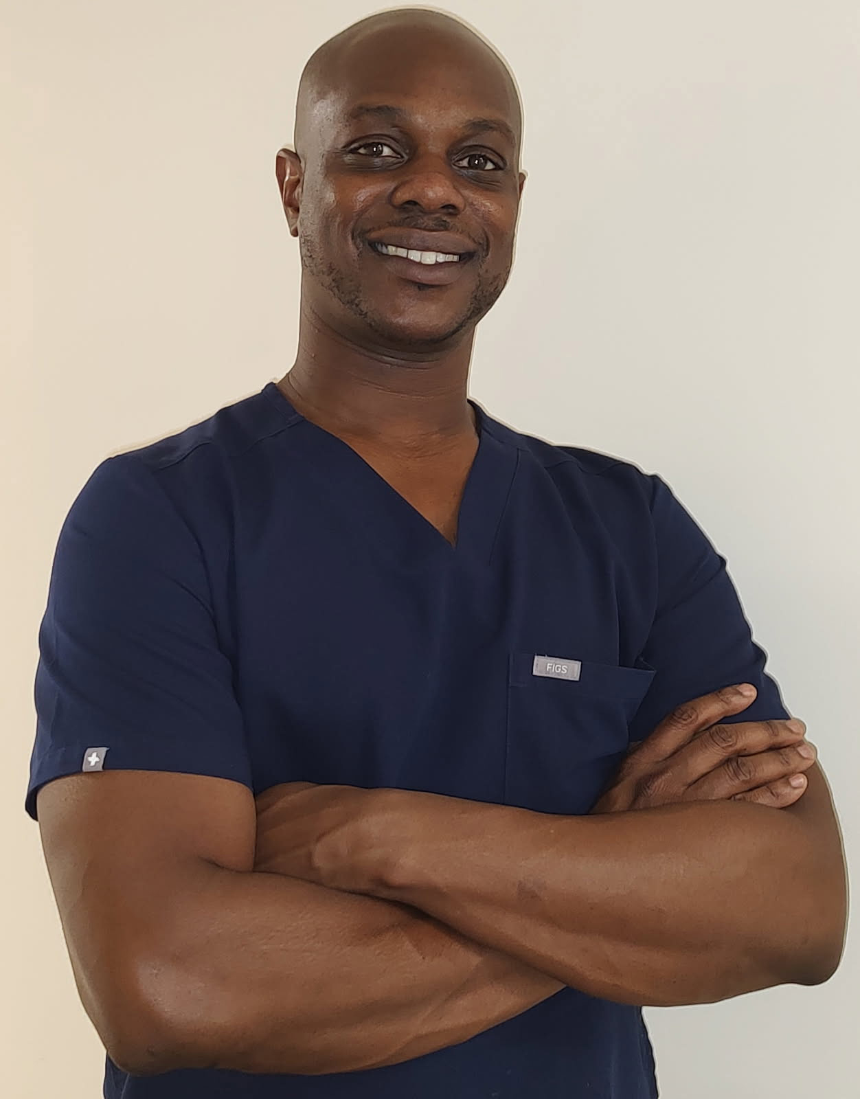 Bobby Ward II, licensed massage and bodywork therapist, smiling in navy scrubs, arms crossed, promoting Unwind Massage and Bodywork's therapeutic services.