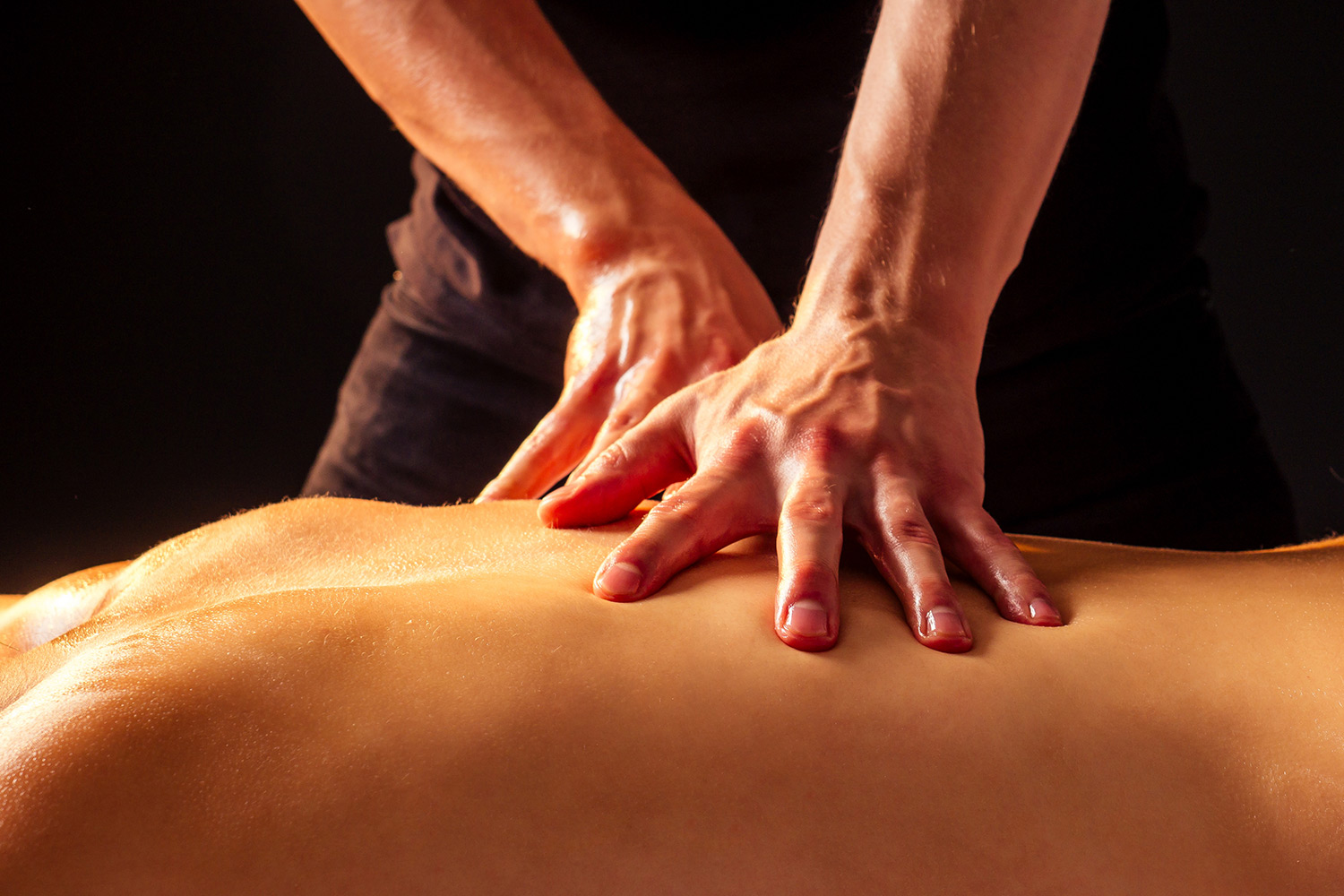 Therapist performing deep tissue massage on client's back, emphasizing therapeutic techniques for pain relief and muscle recovery.