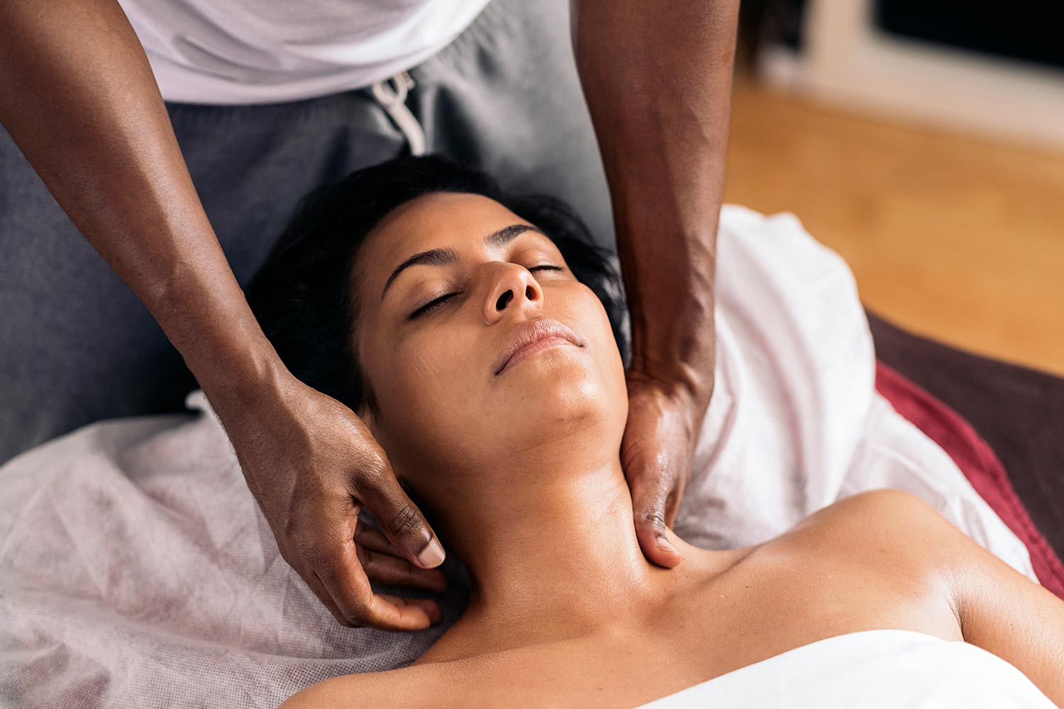 Massage therapist performing a neck massage on a relaxed client, highlighting the soothing experience of the Body Butter Brush Massage for skin health and relaxation.